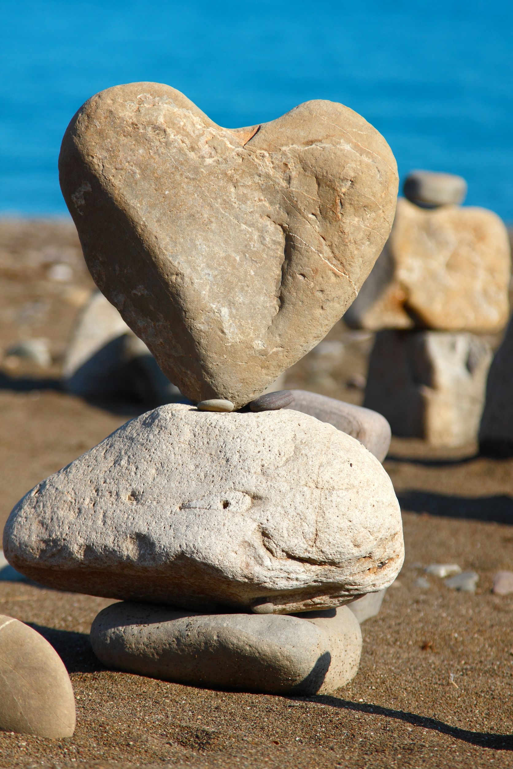 16062164 - heart of rock with balanced stones, pebbles stacks against blue sea