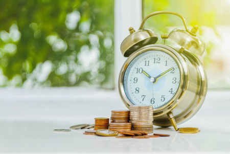 61032978 - alarm clock and money,coins stack and alarm clock on background,finance concept,business background and selective focus.